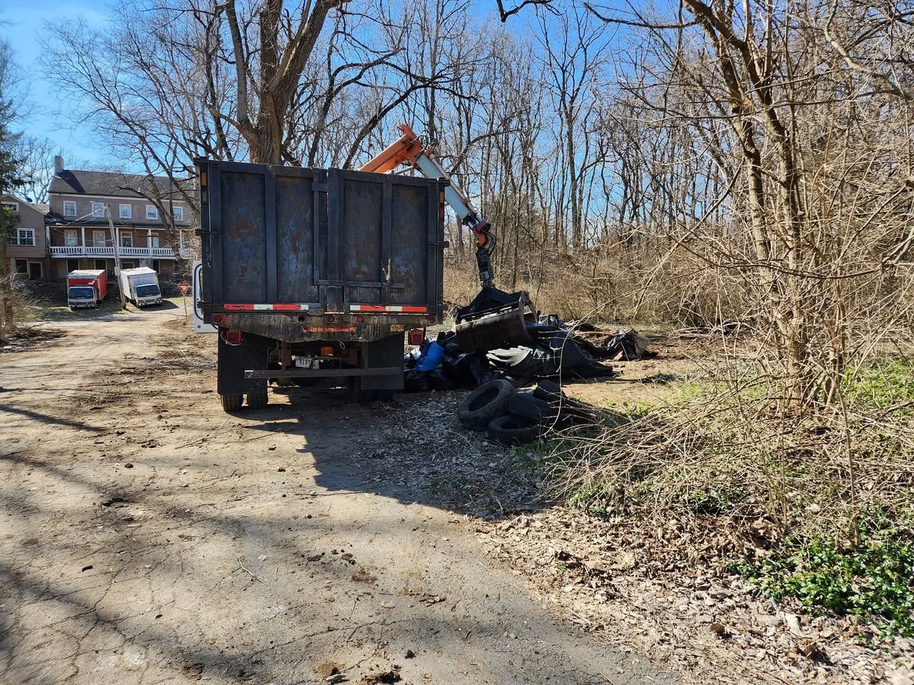 A grapple truck loading bagged debris hauled from an illegal dump site